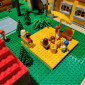 Eine Kinder-Minifigur sitzt im Sandkasten und hat eine Sandburg gebaut, die Eltern sitzen drumrum.