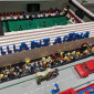 Zu sehen ist ein aus Bausteinen gebautes Fu&szlig;ballstadion, vor dem viele Minifiguren anstehen, weil sie hinein wollen. 